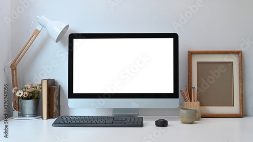 Front view of contemporary workspace with white blank screen monitor computer and equipment on white desk.