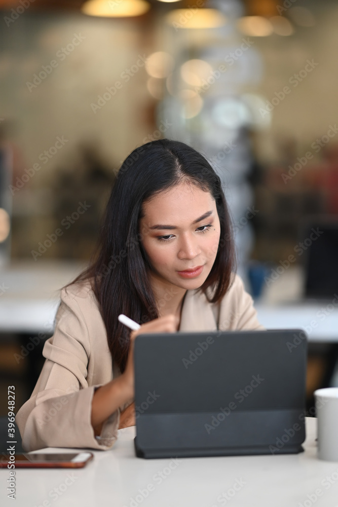Portrait of an attractive business woman is working on computer tablet in office. Portrait of an attractive business woman is working on computer tablet in office.