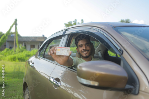 Young indian businessman or employee sitting in car and showing card © PRASANNAPIX