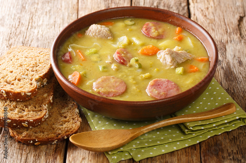 Fotografie Winter pea soup with vegetables, sausages and pork close-up in a bowl on the table