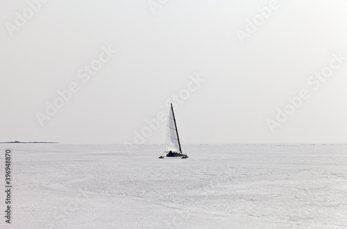 A tourist travels under a sail on a ice-skating ice boat - boeier across the endless expanse of frozen Lake Baikal. Active winter holidays