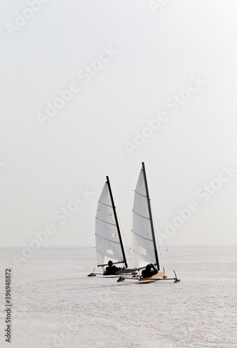 Two tourists in sportswear and safety helmets travel under sails on a speed skating boat - boeier across the vast expanses of frozen Lake Baikal. Active winter recreation