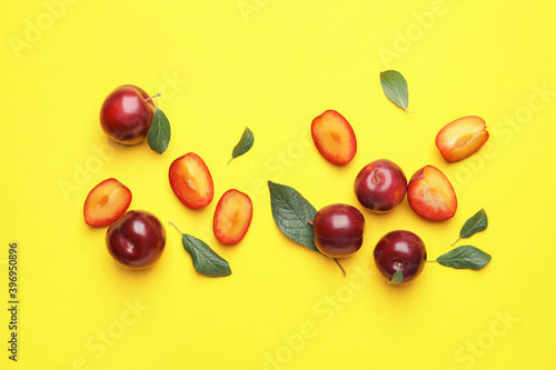 Fresh ripe plums on color background