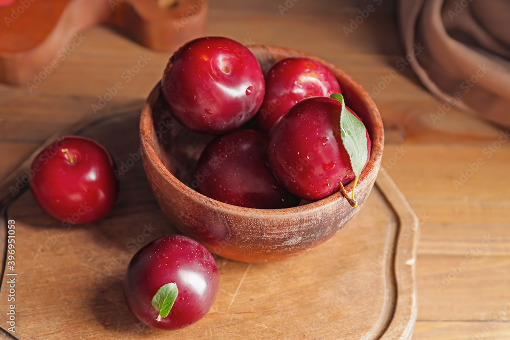 Bowl with fresh ripe plums on wooden table Bowl with fresh ripe plums on wooden table