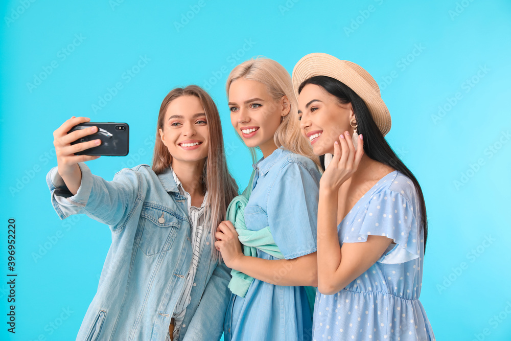 Beautiful young women taking selfie on color background