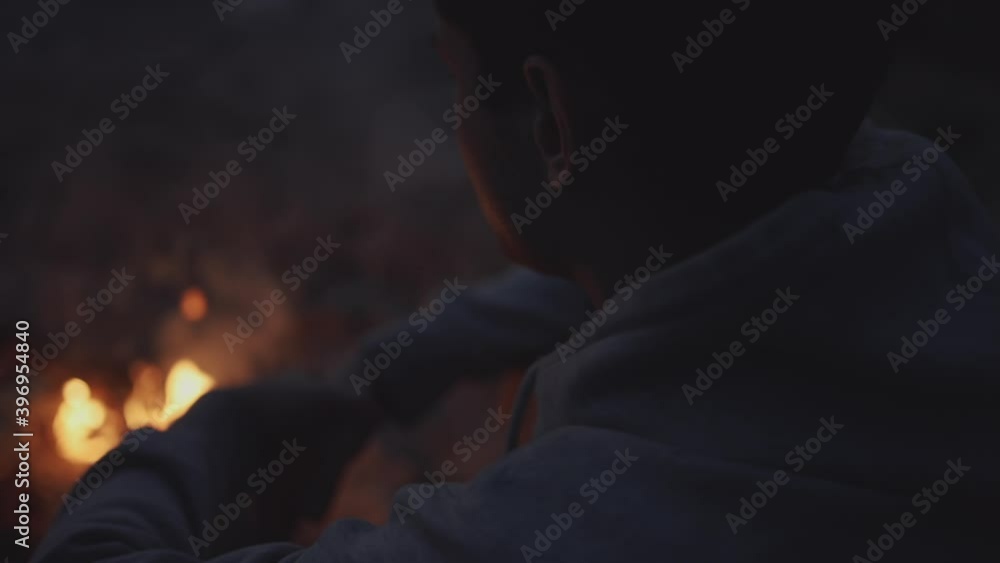A lonely guy sits alone by the fire with sad thoughts. Close shot of a portrait. Self-isolation during the holidays. Evening meditations. The concept of self-isolation, loneliness, vacation. A lonely guy sits alone by the fire with sad thoughts. Close shot of a portrait. Self-isolation during the holidays. Evening meditations. The concept of self-isolation, loneliness, vacation.