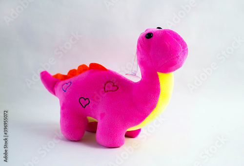 Dragon plush doll  on white background with shadow reflection. Dragon plush stuffed doll on white background. Dino plush toy. Pink stuffed dinosaur toy