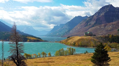 Middle Waterton Lake lakeshore in autumn foliage season sunny day morning. Blue sky, white clouds over mountains in the background. Landmarks in Waterton Lakes National Park, Alberta, Canada. photo