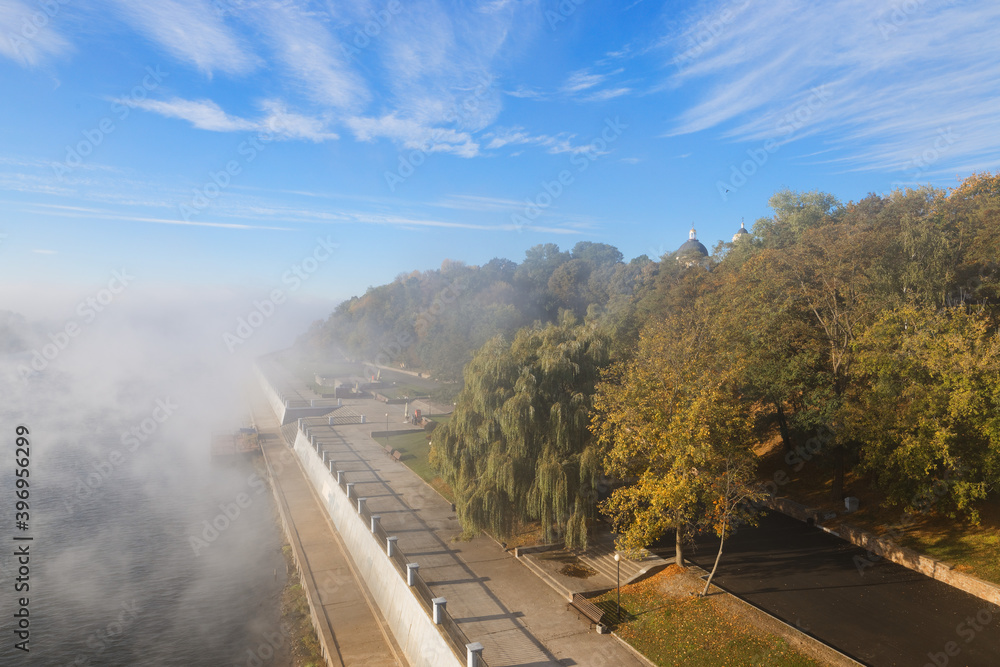 morning fog over the river embankment of the city