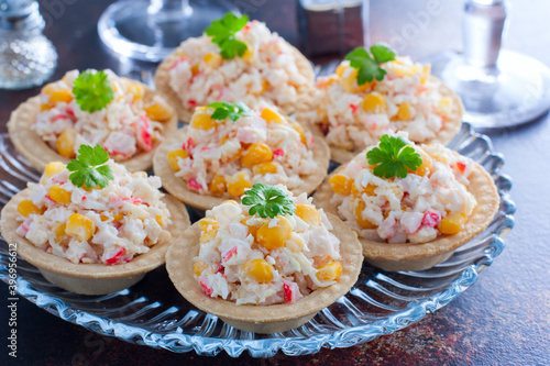 Celebratory tartlets with crab salad and corn on a glass dish and glasses of champagne, horizontal