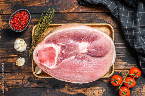 Cut of raw pork knuckle, leg on a cutting board. Farm fresh meat. Wooden dark background. Top view.