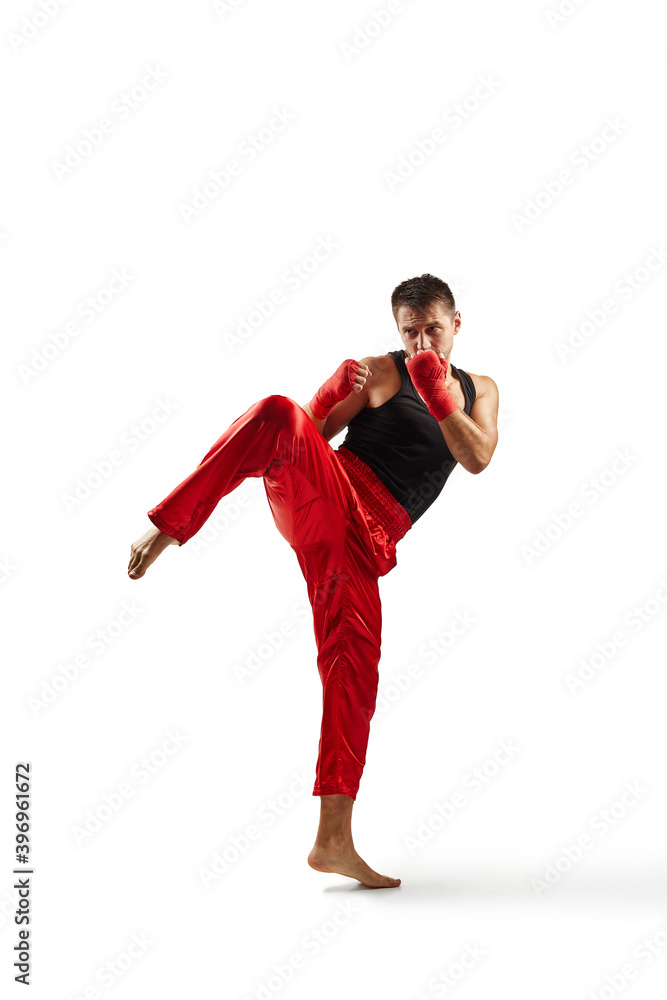 Athletic man in red sports bandages on his hands making kick during boxing exercise, isolated on white background. full lenth Athletic man in red sports bandages on his hands making kick during boxing exercise, isolated on white background. full lenth