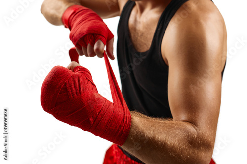 sporty man wraps his hands in red sports bandages before training. Close-up