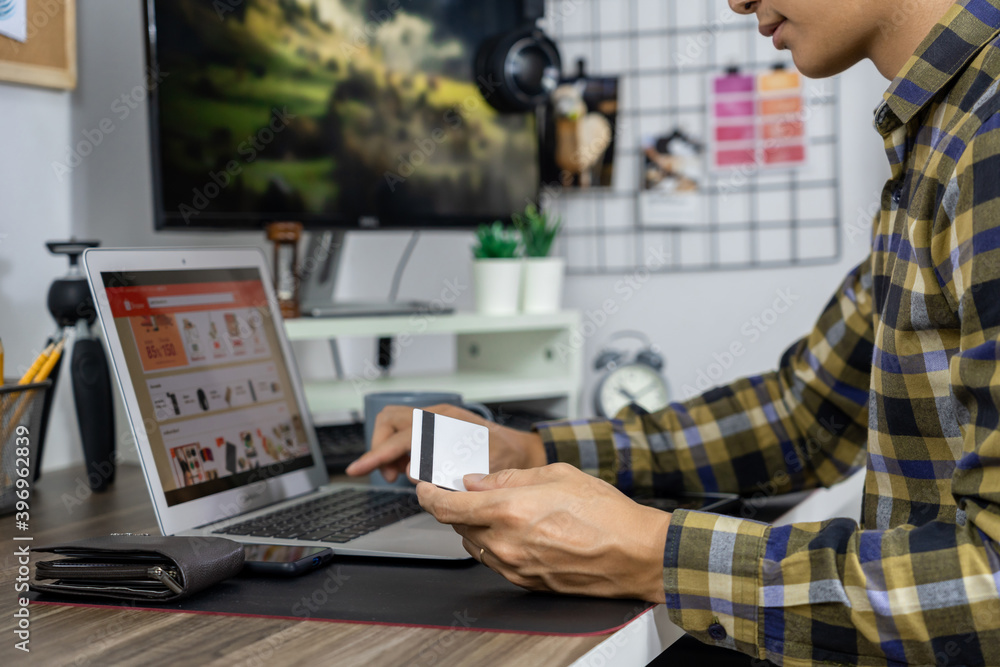 Asian man holding credit card and typing information on internet with laptop at home, online shopping concept. Asian man holding credit card and typing information on internet with laptop at home, online shopping concept.