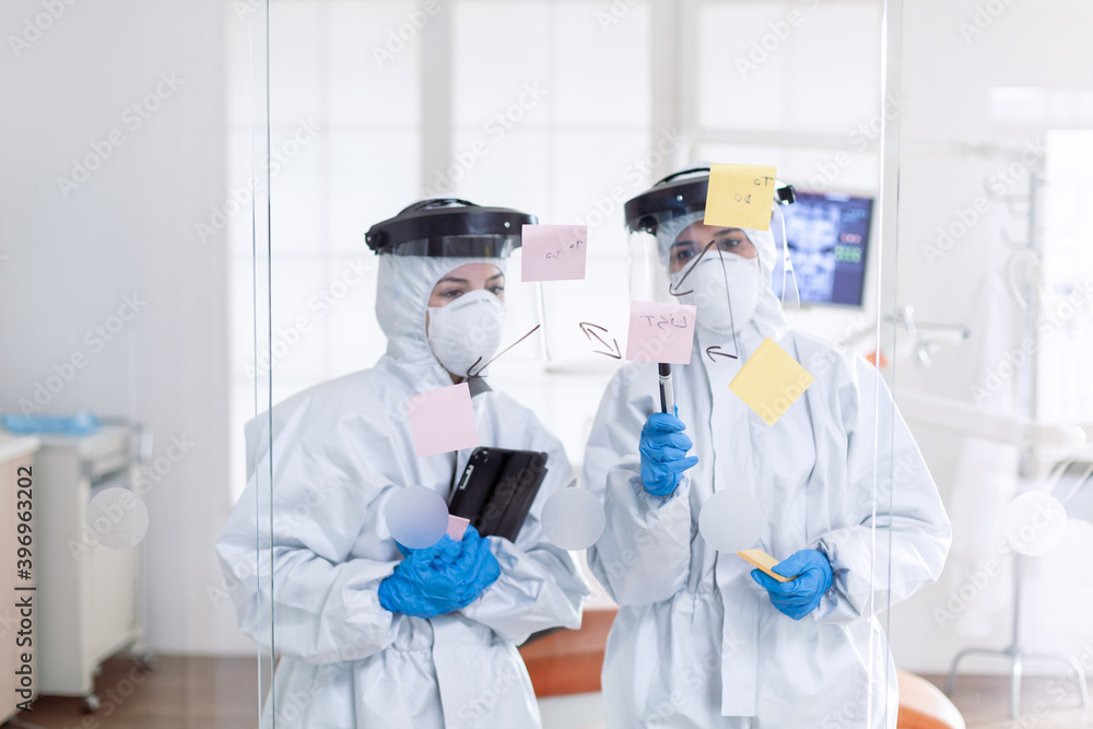 Professional dentists in ppe suit checking schedule during covid19