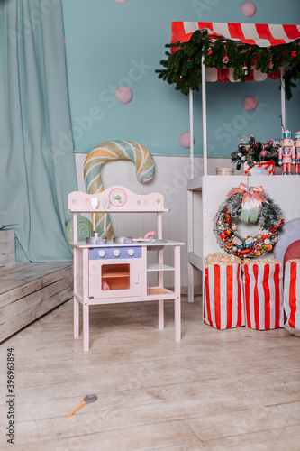 Christmas gifts for kids under the tree. Toy kitchen present for girls. Christmas present under the tree. Toy wooden kitchen and dishes. © Маргарита Щипкова