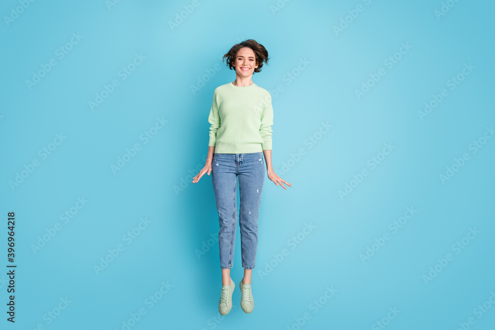 Full size photo of optimistic short hairdo girl jump wear lime sweater jeans sneakers isolated on teal color background Full size photo of optimistic short hairdo girl jump wear lime sweater jeans sneakers isolated on teal color background