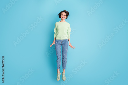 Full size photo of optimistic short hairdo girl jump wear lime sweater jeans sneakers isolated on teal color background