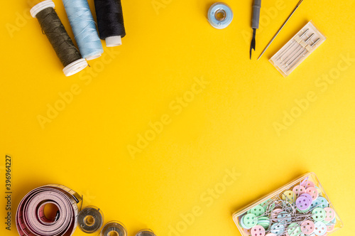 Workspace with creative accessories: scissors, office knife, sewing thread and other sewing accessories on a orange background