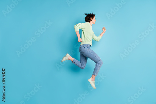 Full size profile photo of optimistic short hairdo girl run wear lime sweater jeans sneakers isolated on teal color background