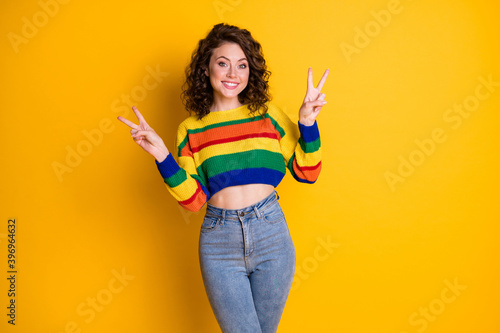 Photo portrait of woman showing two v-signs isolated on bright yellow colored background
