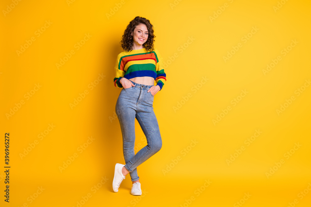 Full length photo of lovely lady palms pockets posing wear striped cropped pullover jeans footwear isolated yellow color background Full length photo of lovely lady palms pockets posing wear striped cropped pullover jeans footwear isolated yellow color background