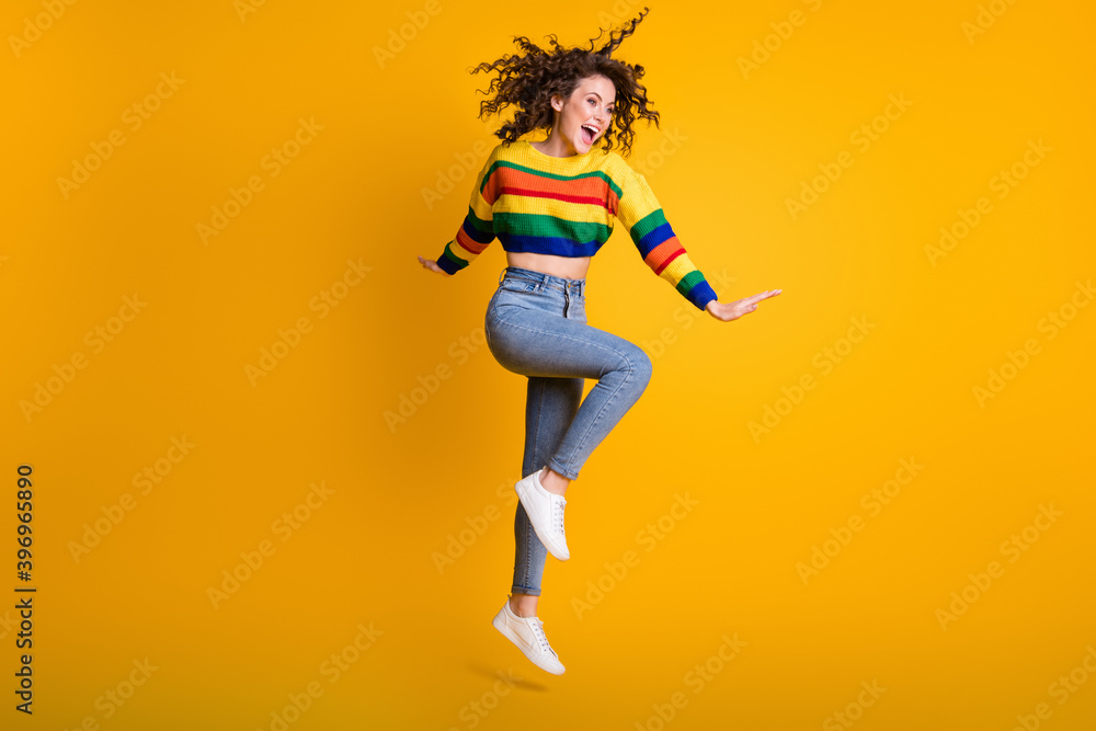Full length photo of funny jumping woman dressed casual colorful sweatshirt looking empty space isolated yellow color background