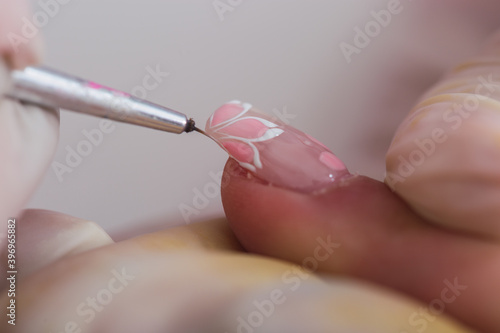 Closeup of brush painting nails. Manicurist working on a woman s nails.
