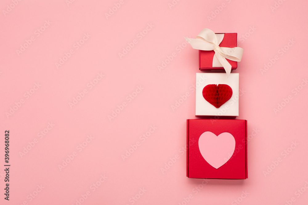 Paper hearts and festive gift boxes on pastel pink background. Valentines day concept.
