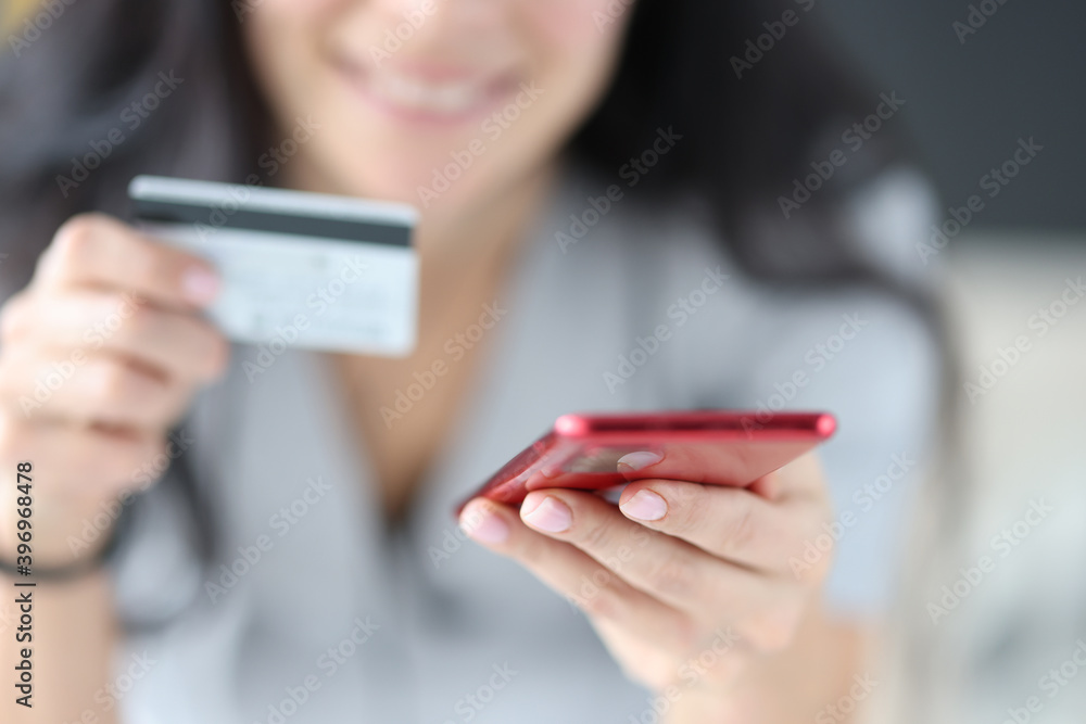 Woman holding bank card and phone in her hands close-up