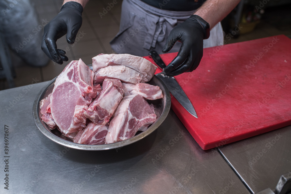A bowl filled with fresh pork meat. Chef working in the kitchen in a pub