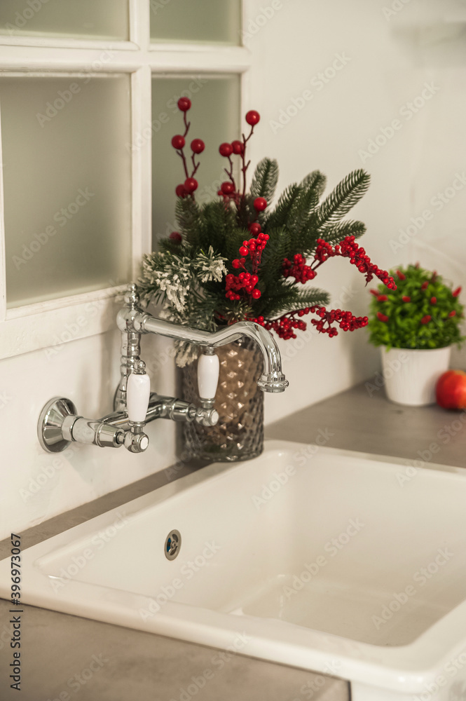 Fototapeta premium New Year's decor of modern kitchen in Scandinavian style. White light rustic kitchen close-up and copy space. Hygge kitchen details New year concept. White gray kitchen room organization. Pure water a