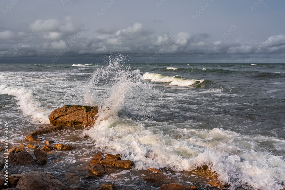 Empty rocky beach and stormy sea in cloudy weather