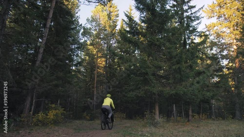 The man travel on mixed terrain cycle touring with bike bikepacking outdoor. The traveler journey with bicycle bags. Stylish bikepacking, bike, sportswear in green black colors. Magic forest park. photo