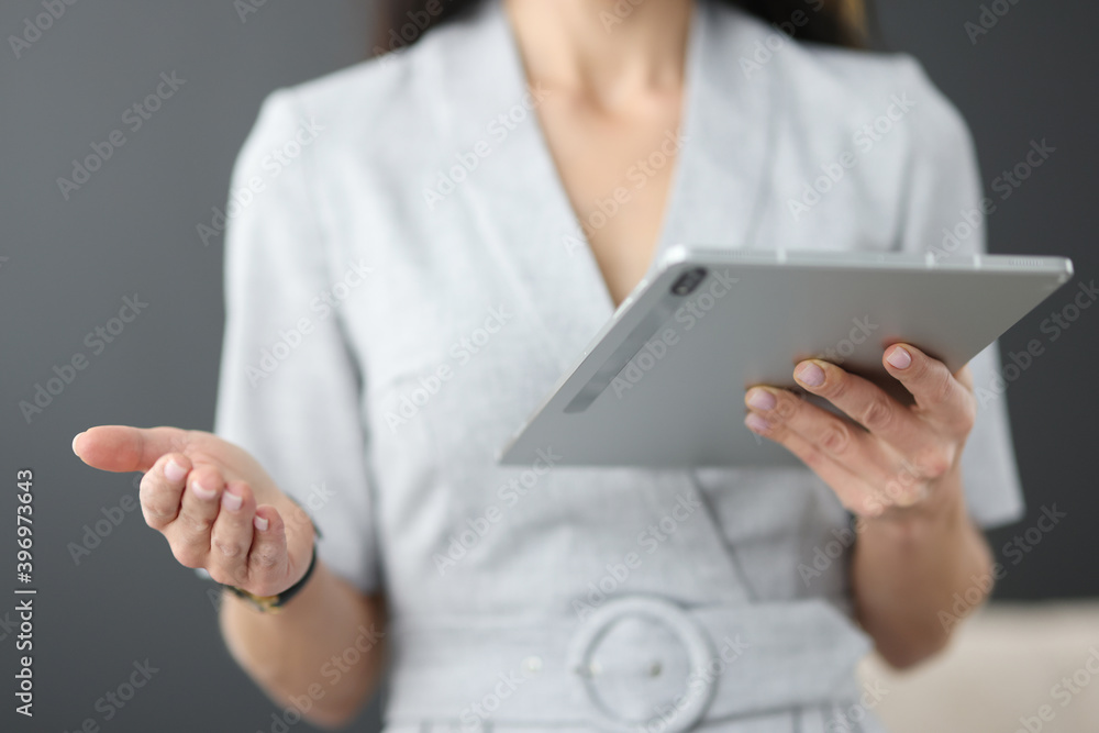 Business woman holding tablet in hands and waving her hand in office Business woman holding tablet in hands and waving her hand in office