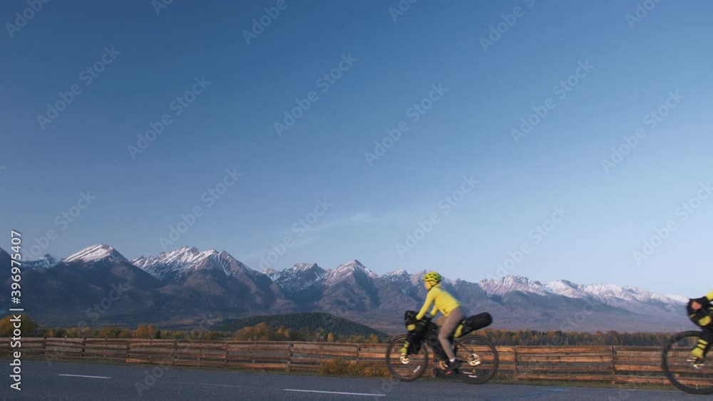 The man and woman travel on mixed terrain cycle touring with bikepacking. The love couple journey with tent in nature with bicycle bags. Stylish bikepacking, bike, sportswear in green black colors. The man and woman travel on mixed terrain cycle touring with bikepacking. The love couple journey with tent in nature with bicycle bags. Stylish bikepacking, bike, sportswear in green black colors.