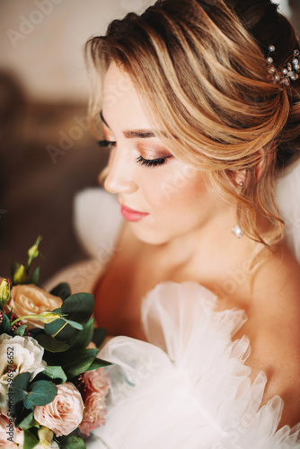 Bride with a bouquet of flowers in her hands and luxurious makeup and hairstyle