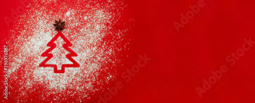 Flour scattered in shape of Christmas tree on red background with star anise. New year horizontal banner for website or social networks with space for text. Design for recipes, bakery or pastry shop