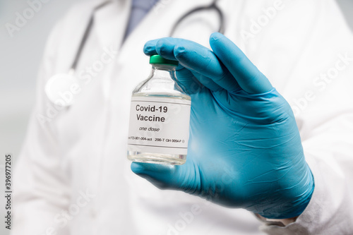 Close up of doctor's hand in medical gloves with a Covid-19 vaccine bottle photo