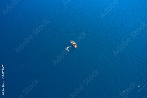 High-speed yacht of white color  on blue water in the rays of the sun top view. Travel - image. Water scooter movement close to the yacht aerial view. © Berg