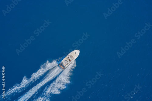 Aerial view of a boat in motion on blue water. luxury motor boat. Top view of a white boat sailing in the blue sea. Drone view of a boat sailing at high speed. © Berg