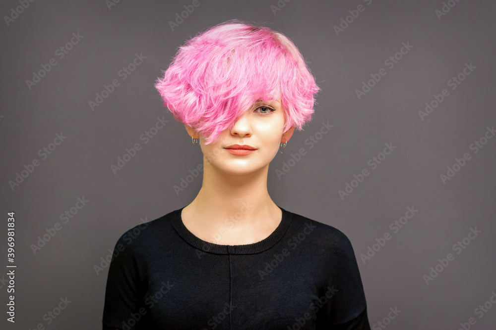 Portrait of fashion model young woman with stylish dyed pink hair in black clothes on dark background
