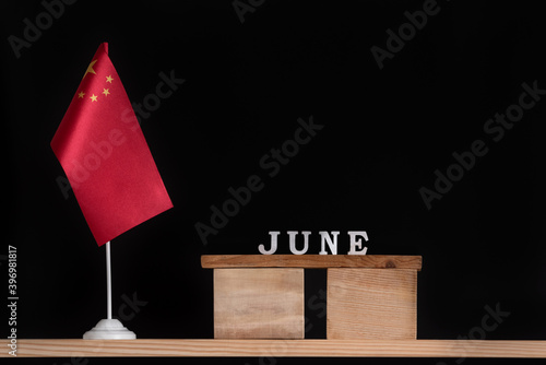 Wooden calendar of June with Chinese flag on black background. Holidays of China in June.
