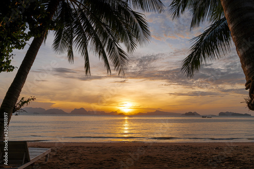 sunrise morning on sand beach between coconut tree, sun beam reflection on calm sea at Koh Yao Noi island, Thailand