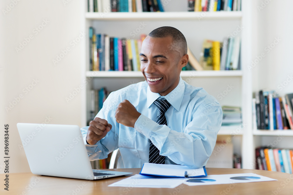 Laughing and cheering african american businessman working at computer Laughing and cheering african american businessman working at computer