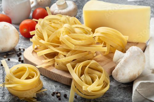 Fettuccine with ingredients. Fettuccine on a wooden Board with cream and mushrooms. Fettuccine with cheese.