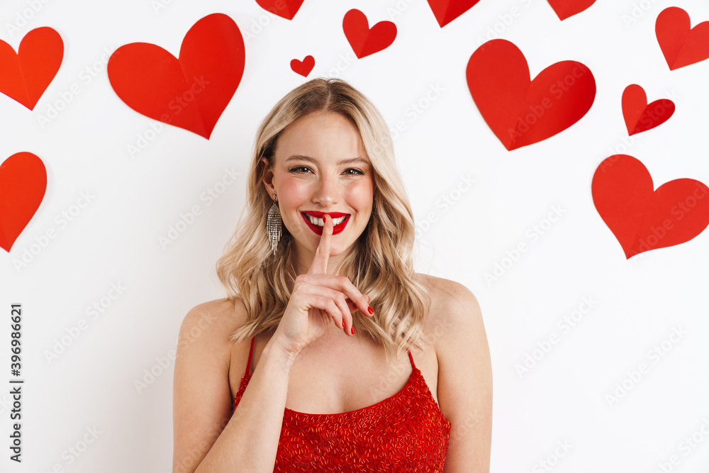 Happy blonde woman in red dress showing silence gesture Happy blonde woman in red dress showing silence gesture