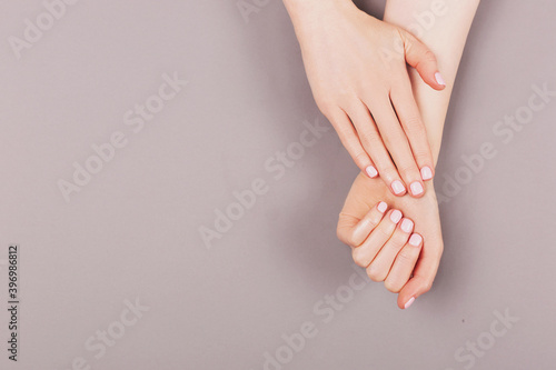 Manicure and nail care concept. Minimal composition of the woman hands on the grey background. Classic pink nail polish. Flat lay, top view.