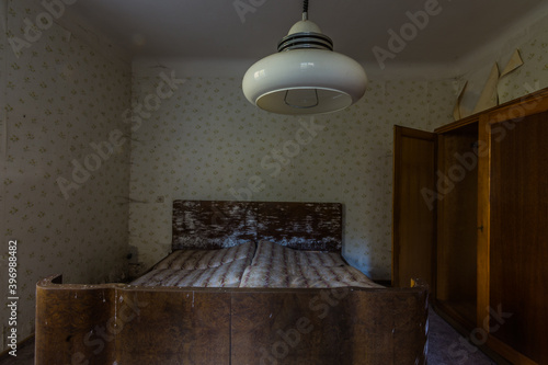 moldy wooden bed and large lamp in a old abandoned house