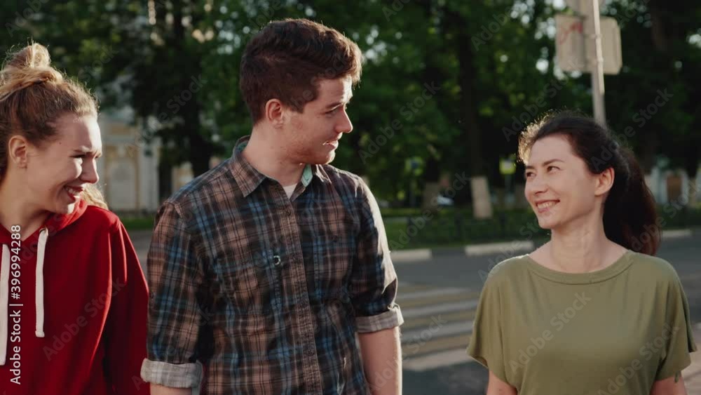 Happy smiling teenage friends walking along the sunny streets of the city together. Young guys laughing, strolling in the park and talk to each other holding hands. Concept of spending time together. Happy smiling teenage friends walking along the sunny streets of the city together. Young guys laughing, strolling in the park and talk to each other holding hands. Concept of spending time together.